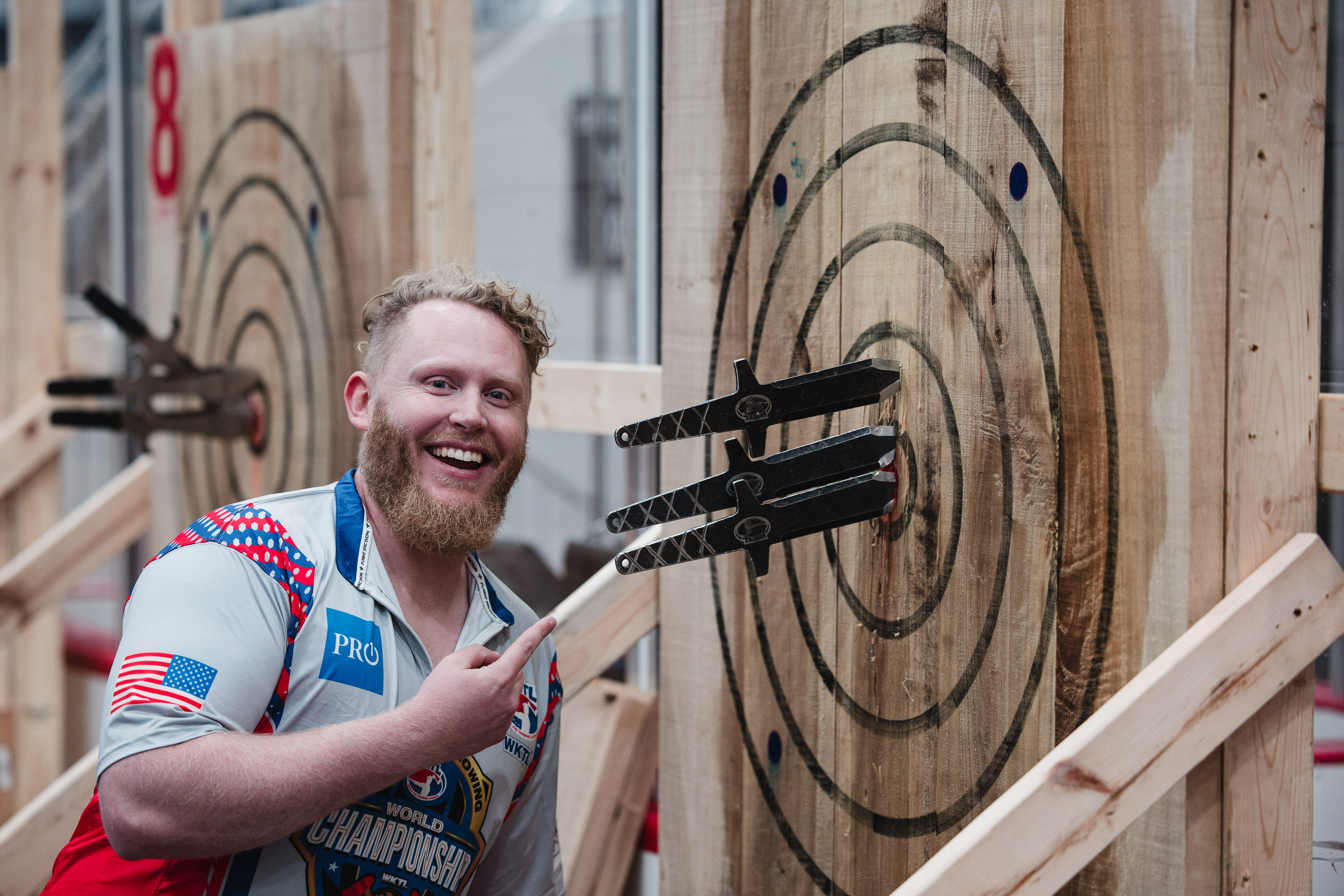 A thrower beside a regulation WKTL target with knives in the board