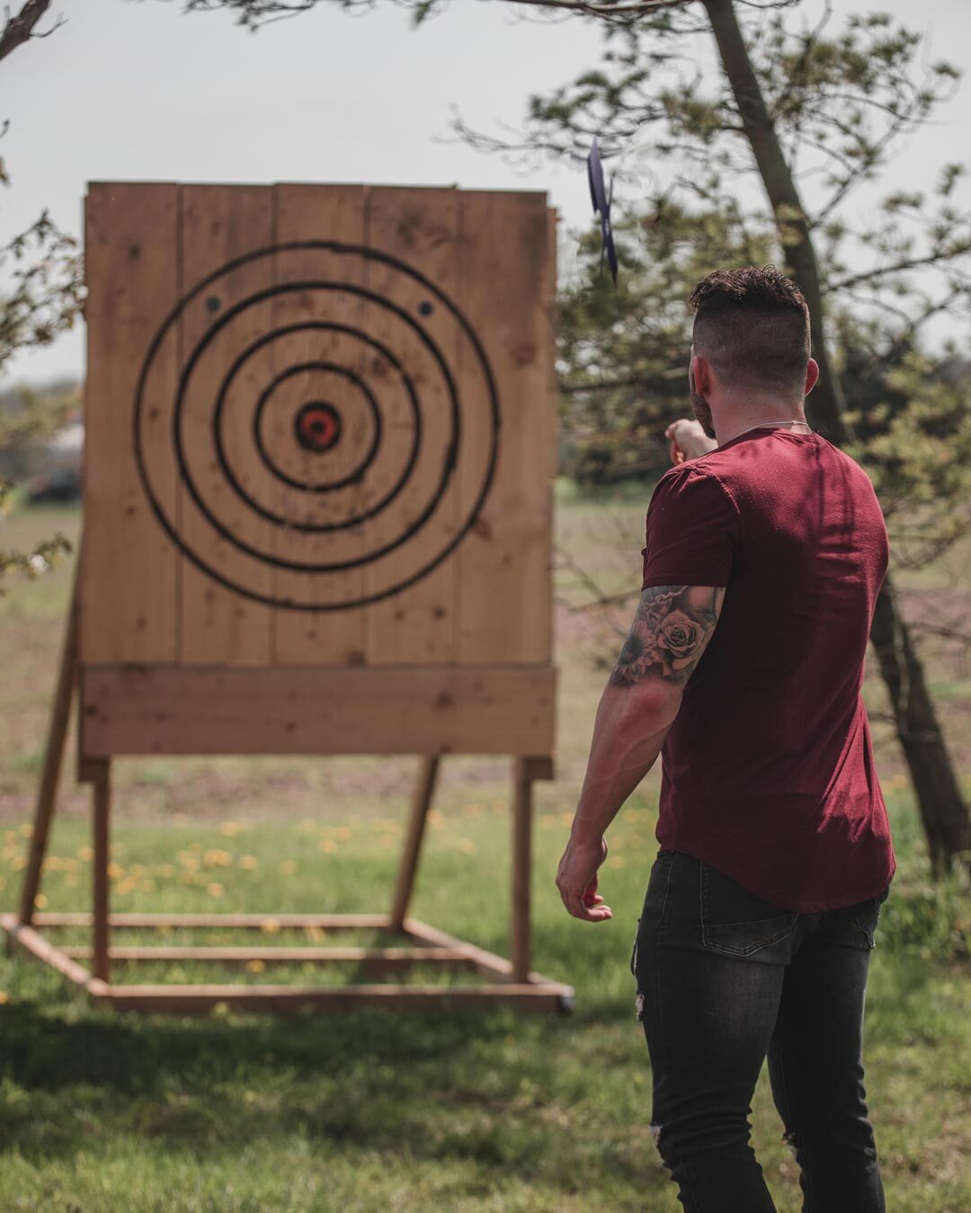 A thrower lining up a knife throw at an outdoor target during a league session