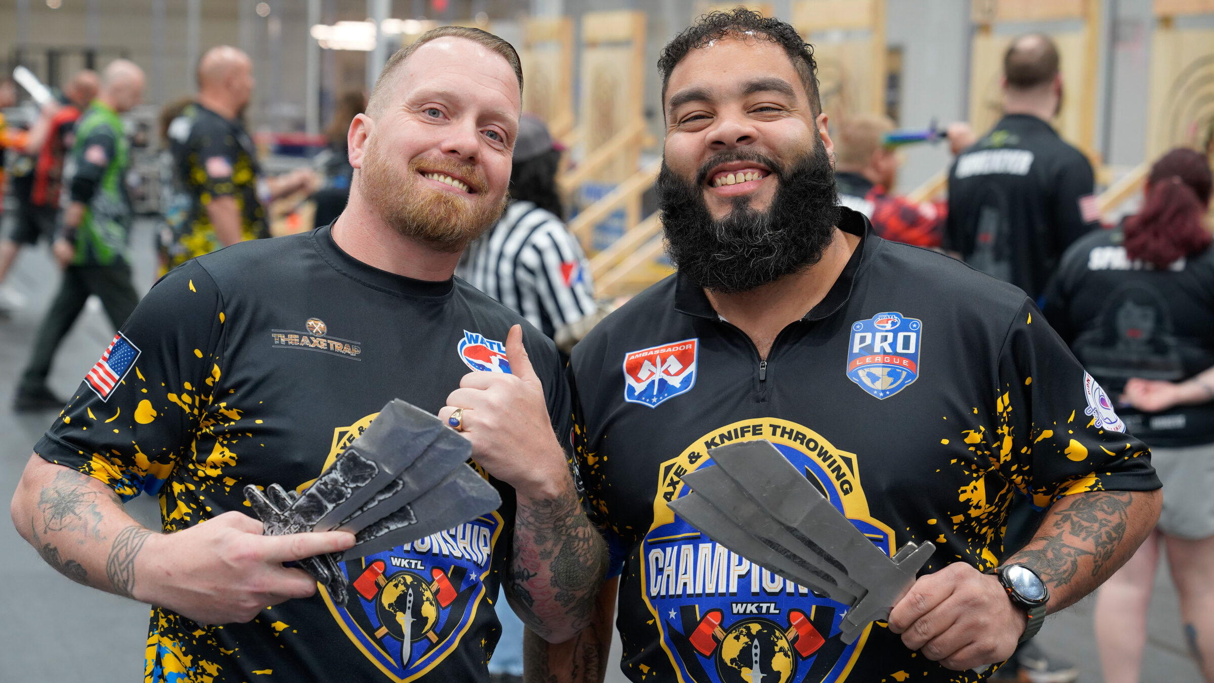 Two throwers in WKTL jerseys holding throwing knives at a WKTL-affiliated venue